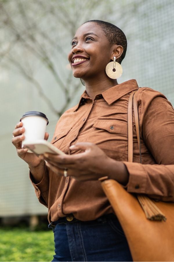 Girl with a coffee mug and phone smiling